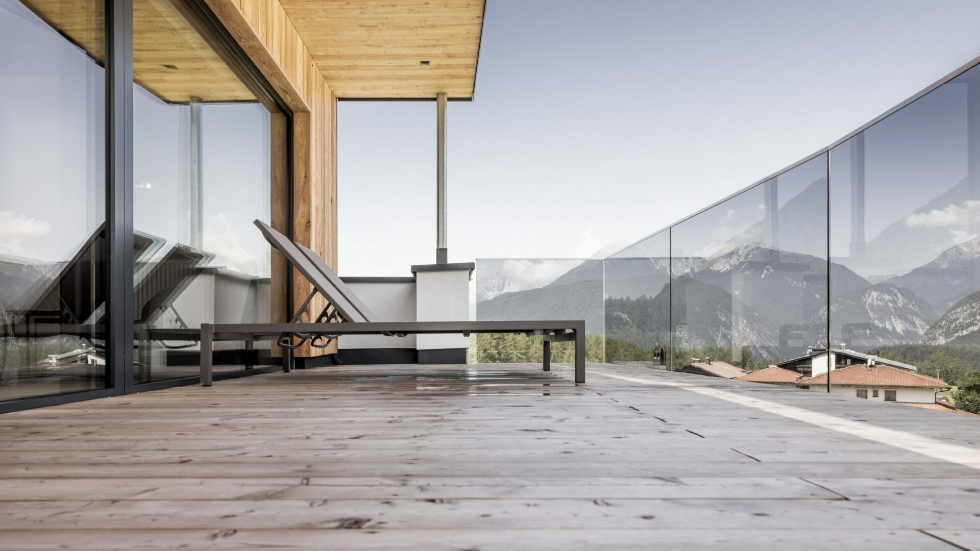 Moderne Terrasse mit Bergblick und Liege.