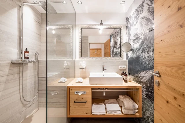 Modernes Badezimmer mit Dusche und Holzregalen.