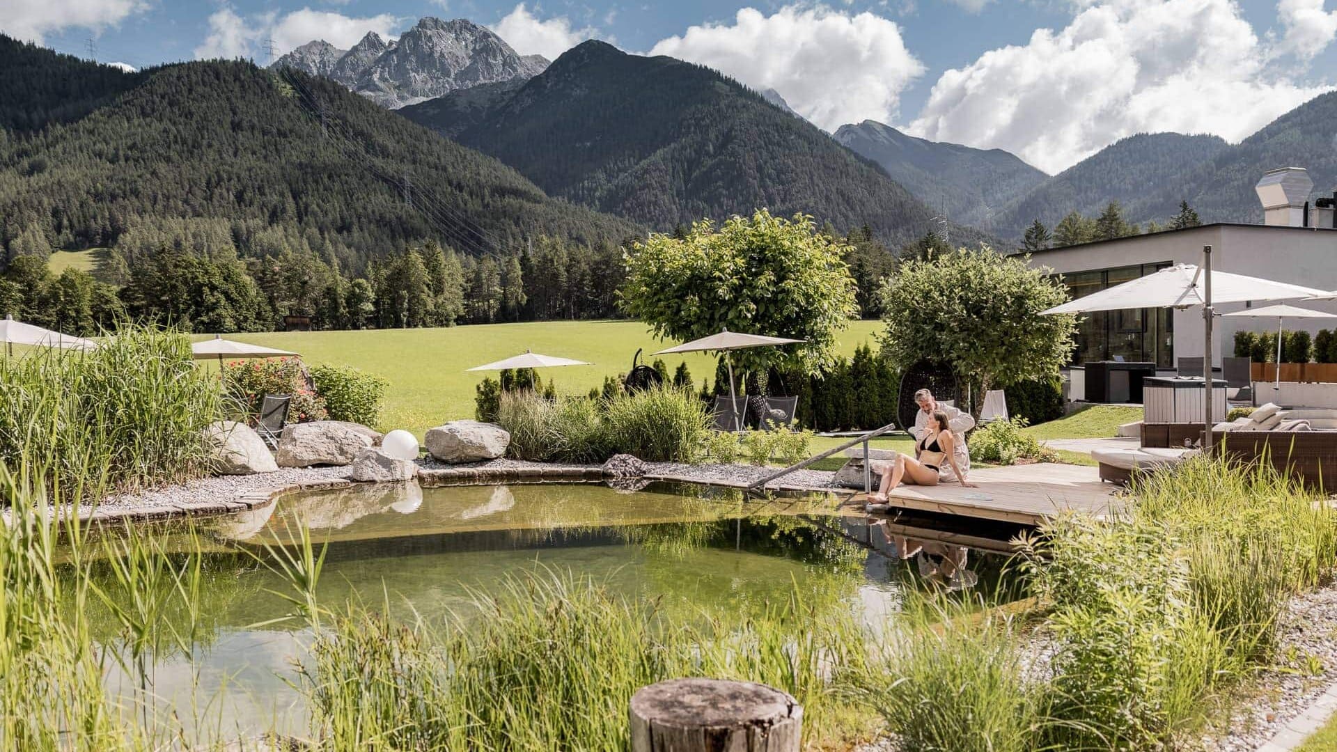 Frau entspannt am Naturpool mit Bergblick.