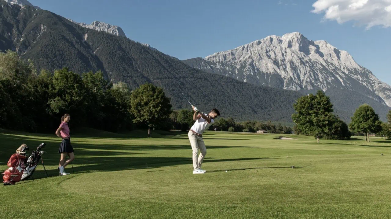Golfspieler mit Berglandschaft im Hintergrund.