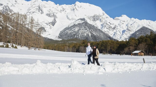Paar wandert durch verschneite Winterlandschaft.