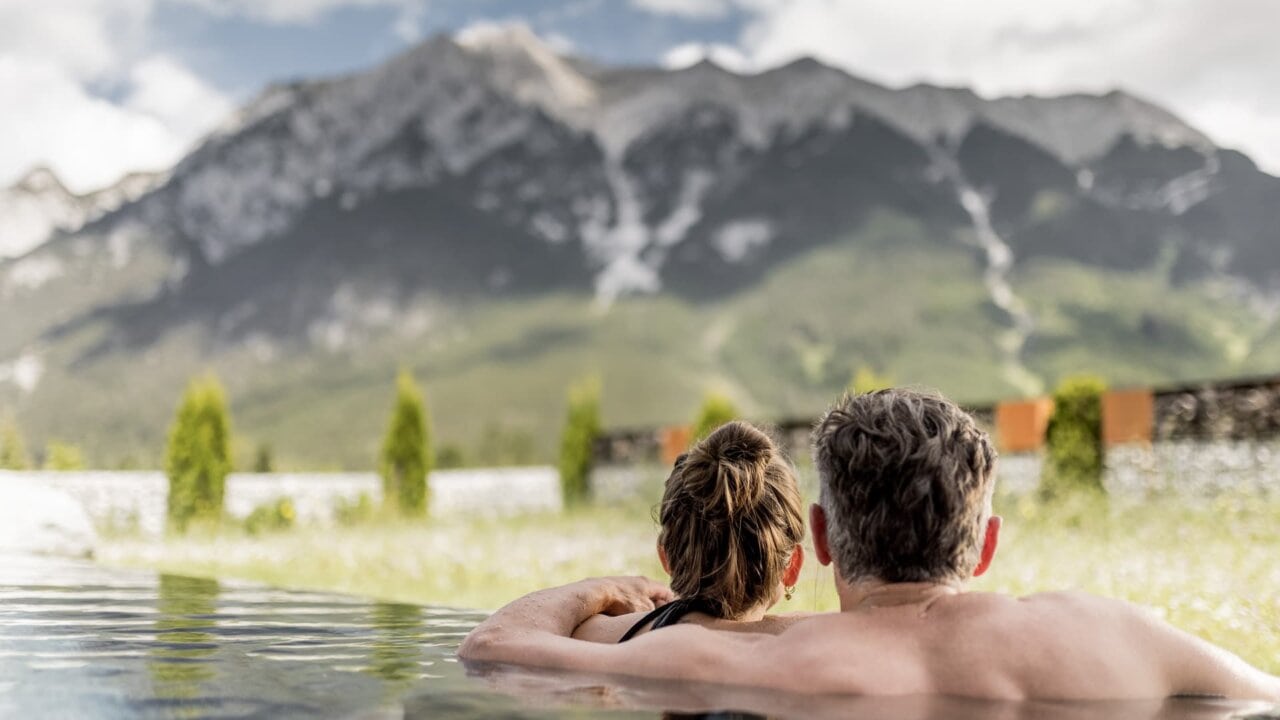Paar entspannt in einem Pool mit Bergblick.