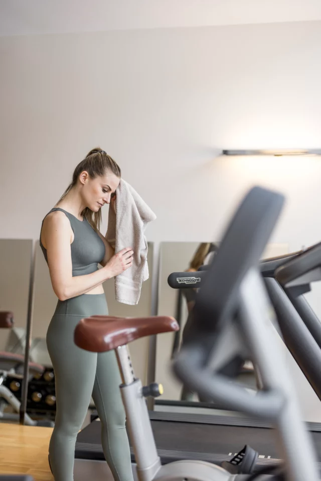 Frau wischt Schweiß im Fitnessstudio ab.