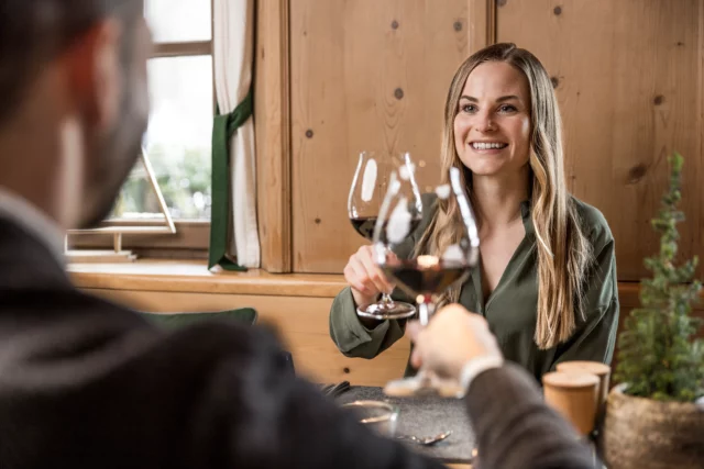 Zwei Personen stoßen mit Rotwein an.