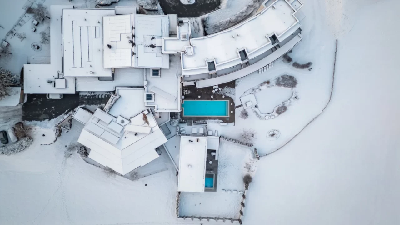 Luftaufnahme eines verschneiten Hauses mit Pool.