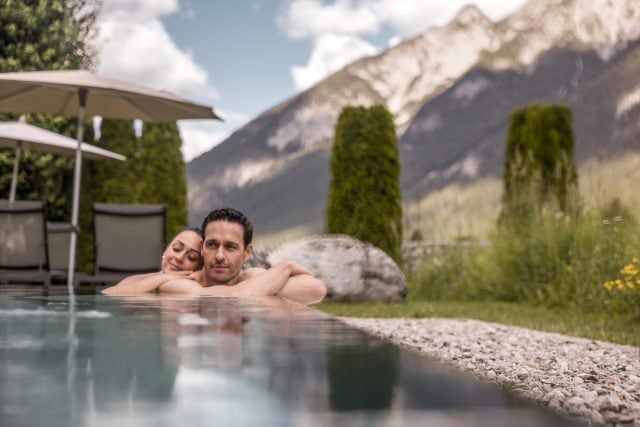 Ein Paar entspannt in einem Pool mit Bergblick.