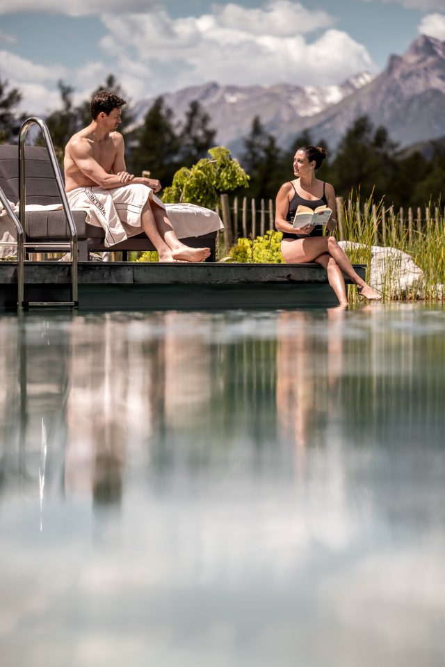 Ein Mann und eine Frau entspannen sich am Pool mit Bergblick.