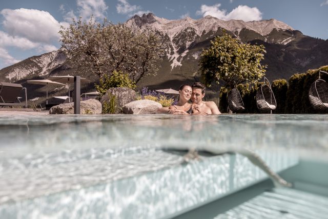 Ein Paar entspannt in einem Pool mit Bergblick und Hängekörben