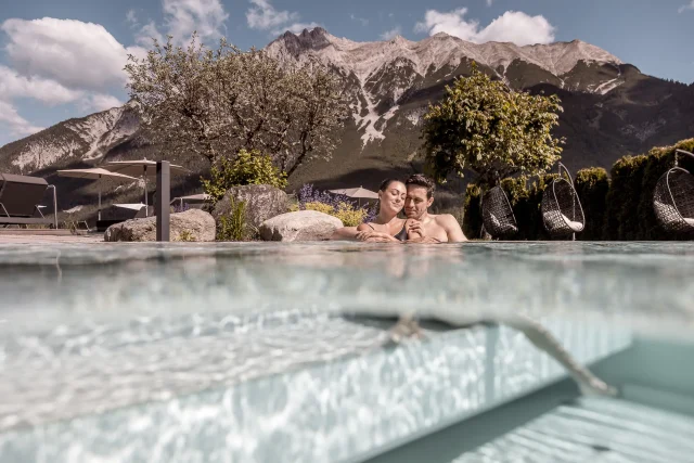 Ein Paar entspannt in einem Pool mit Bergblick und Hängekörben