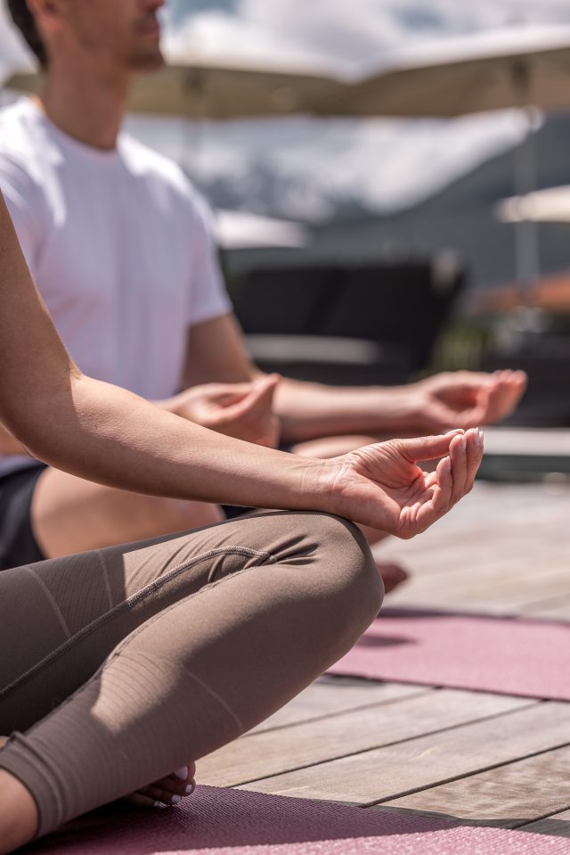 Paar in der Natur beim Yoga, die Hände in meditativer Geste.